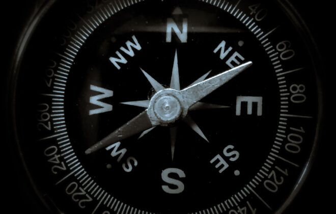 Close-up of a compass needle pointing north, symbolizing guidance and direction.