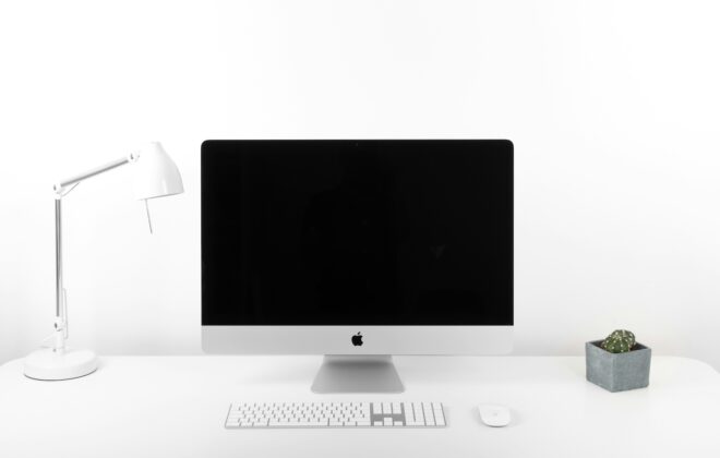 Streamlining MVP Development with AI. Minimalist workspace with an iMac, white desk lamp, and potted plant, symbolizing a clean and efficient work environment.